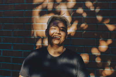 Portrait of smiling teenager against brick wall