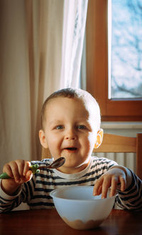 Portrait of cute smiling boy eating food at home