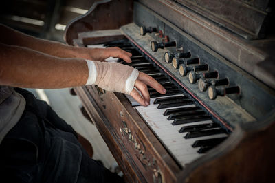 Midsection of man playing old piano