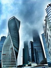 Low angle view of modern buildings against cloudy sky