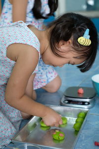 Cute girl playing with clay in tray at home