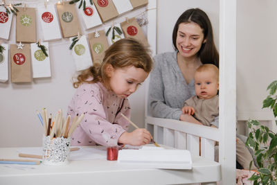 Toddler child writing christmas letter and doing advent calendar tasks in kids room. festive family