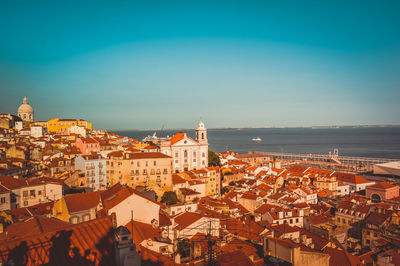 High angle view of townscape by sea against blue sky