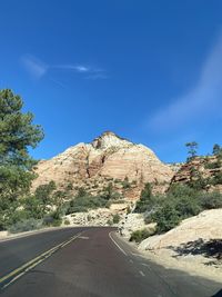 Road by mountain against blue sky