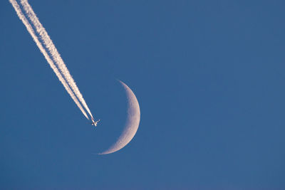 Low angle view of airplane flying against clear blue sky