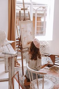 Rear view of woman sitting on chair at home