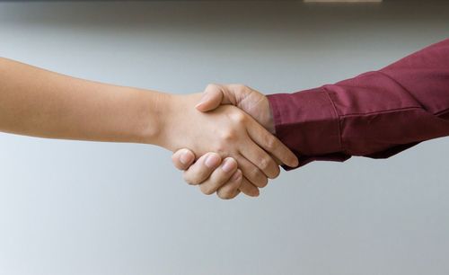 Cropped image of people shaking hands against white background