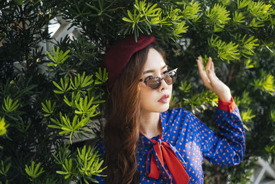 Young woman standing by tree outdoors