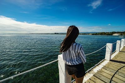 Rear view of woman looking at sea against sky