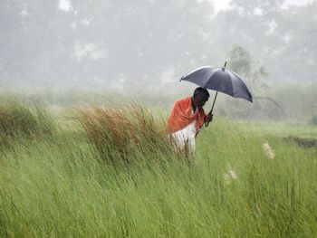 Man holding umbrella on field during rainy season