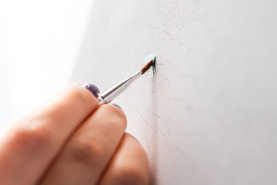 Close-up of hand holding syringe against white background