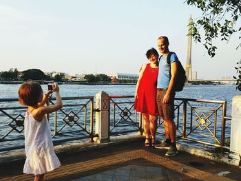 Full length of woman photographing while standing on railing