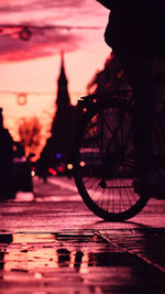 Silhouette bicycle by street against sky during sunset