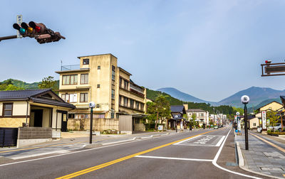 Road by buildings against sky