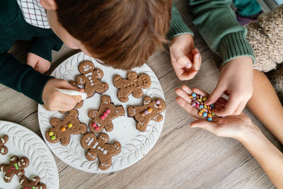 High angle view of kids decorating gingerbread cookies at home