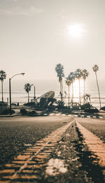 Empty road leading towards sea against sky during sunset