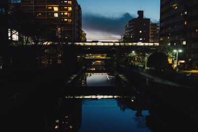 Reflection of illuminated bridge in city at night