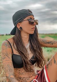 Portrait of tattooed woman wearing sunglasses standing outdoors