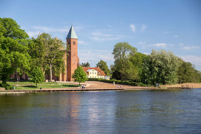 River by trees and buildings against sky