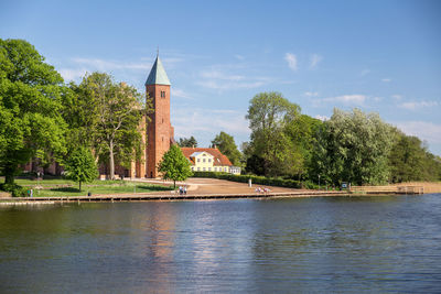 River by trees and buildings against sky