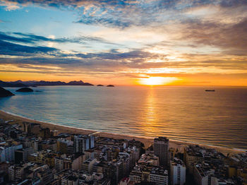 Scenic view of sea by buildings against sky during sunset