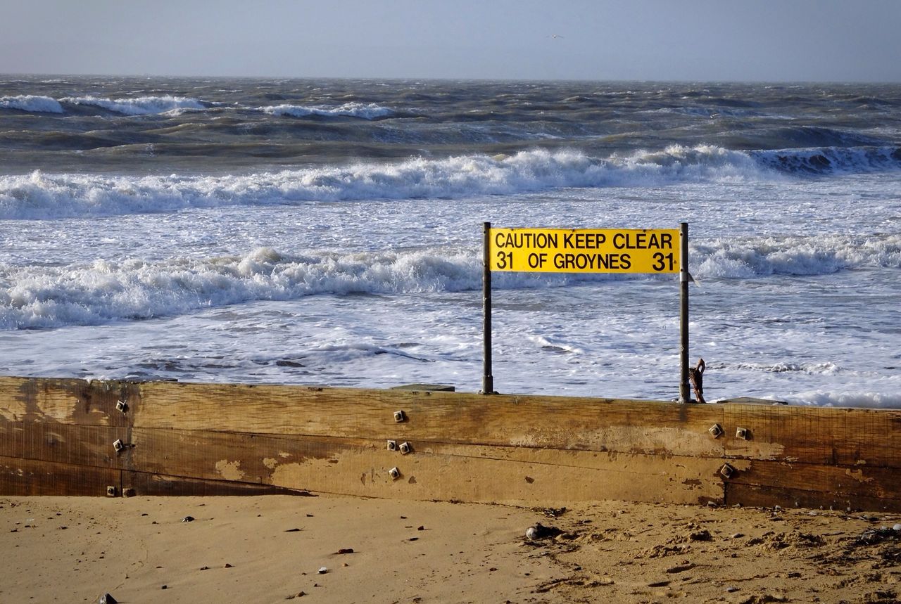 sea, text, western script, beach, water, horizon over water, communication, shore, information sign, sand, wave, guidance, sign, warning sign, capital letter, surf, sky, nature, scenics, tranquility