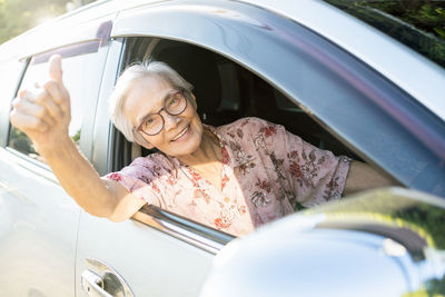 Portrait of woman sitting on car window