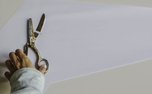 Close-up of hand holding metal against wall