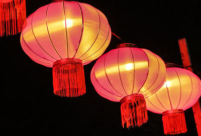 Low angle view of illuminated lanterns hanging against sky at night