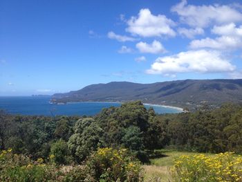 Scenic view of sea and mountains against blue sky