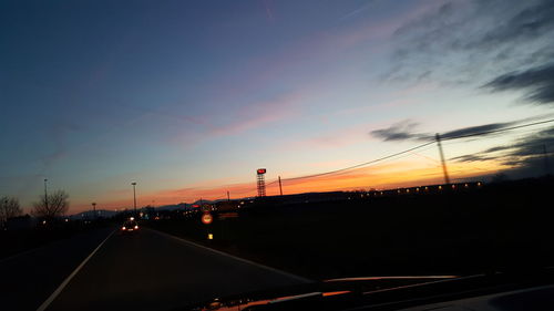 Cars on highway against sky during sunset