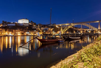 Illuminated bridge over river in city at night