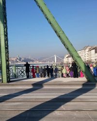 People on bridge in city against clear sky