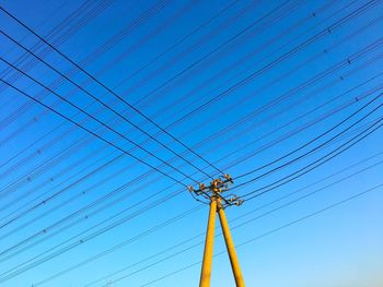 Low angle view of electricity pylon against blue sky