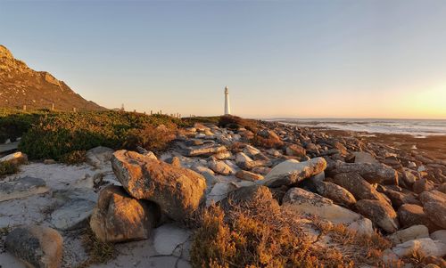 Rocks on beach against sky during sunset