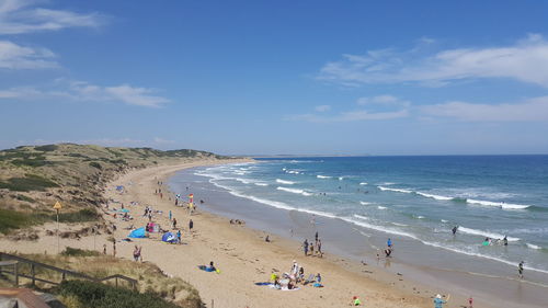 Panoramic view of people on beach against blue sky