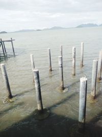 Wooden posts in sea against sky