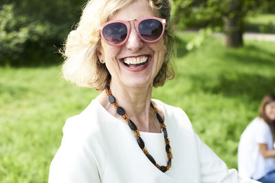 Portrait of happy senior woman wearing sunglasses in park