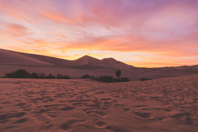 Sand dunes in desert against cloudy sky