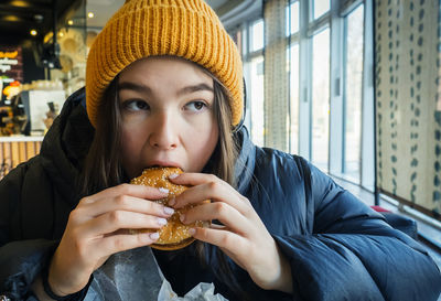 Teen girl eating a hamburger in a cafe