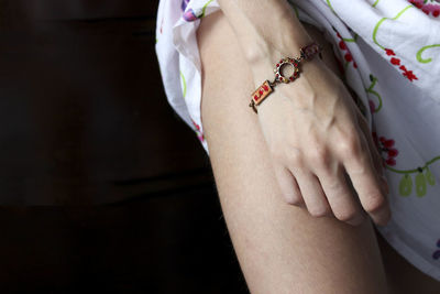 Close-up of woman wearing bracelet against black background