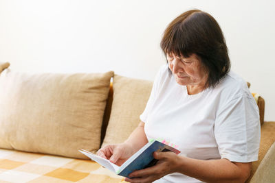 Young woman using laptop while sitting on sofa at home