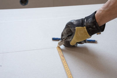 Carpenter cutting through building material with a work glove on.