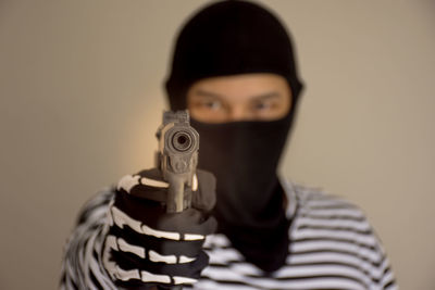 Portrait of criminal holding handgun with his face covered