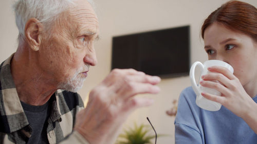 Nurse drinking coffee with senior man in rehab