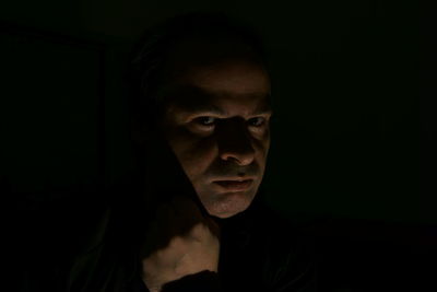 Close-up portrait of man showing fist in darkroom