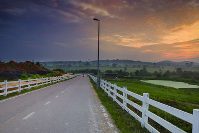 Empty road against sky during sunset