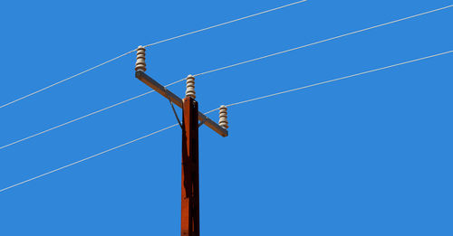 Low angle view of power lines against clear blue sky
