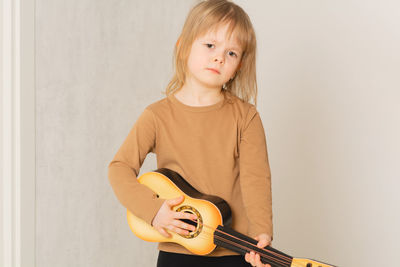 Funny child at home learning to play the guitar. portrait of a child with closed eyes smiling