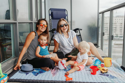 Young mothers spending time together with children babies on a balcony at home. lgbtq female parents 